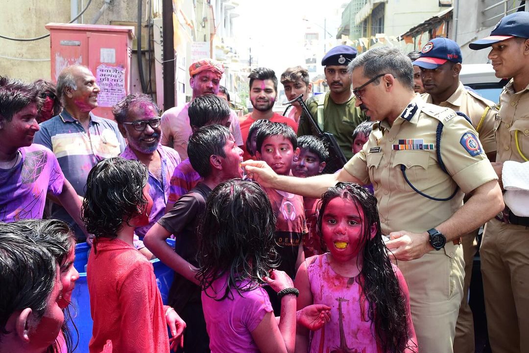 Nagpur Police Commissioner Dr. Ravindra Singal playing Holi with children and distributing sweets.