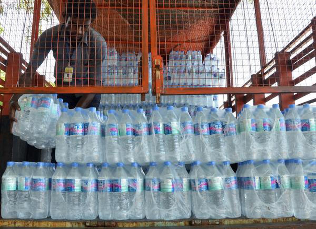 Railway inspection team confiscating unauthorized water bottles at a railway station.