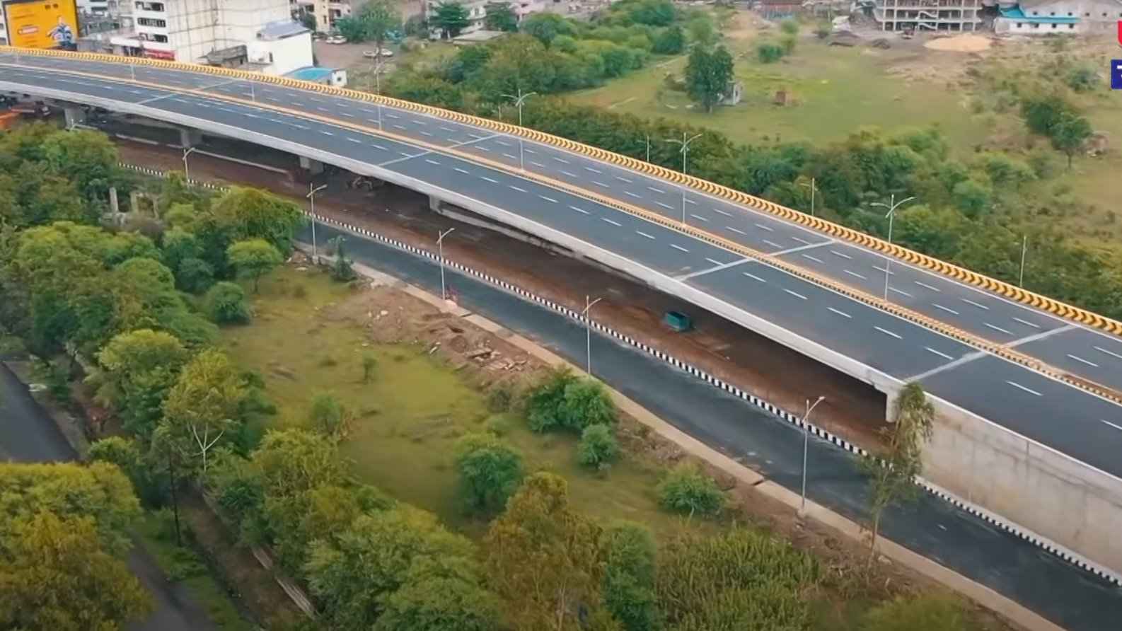Damaged Butibori flyover under repair with green nets and support structures installed.