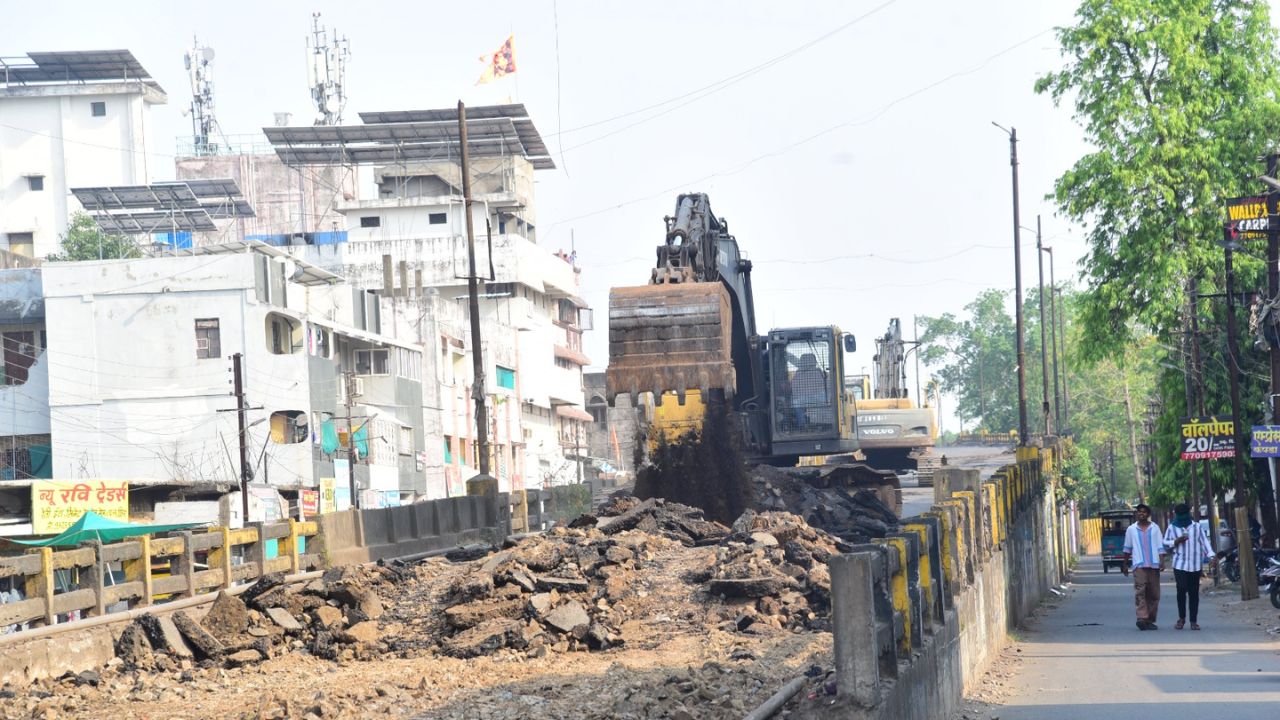 A halted flyover demolition site with cranes and debris under a cloudy Nagpur sky.